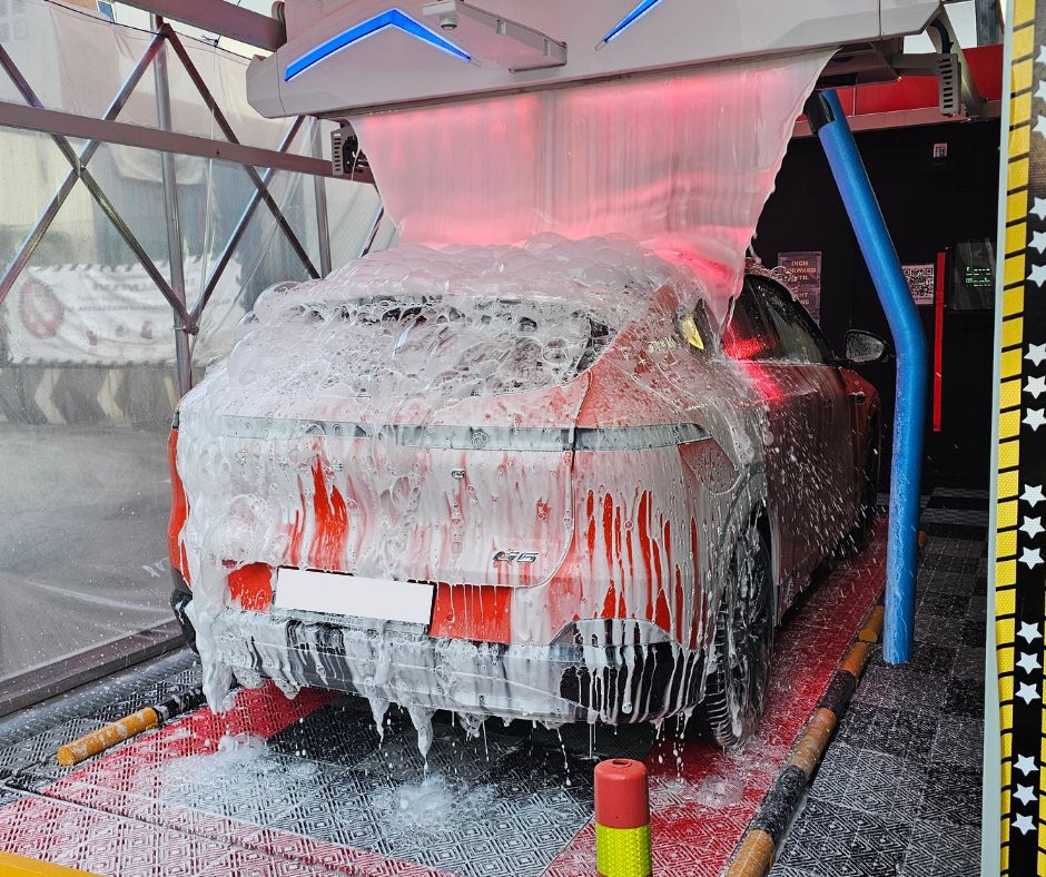 A car covered in Lava Foam inside an automated wash bay