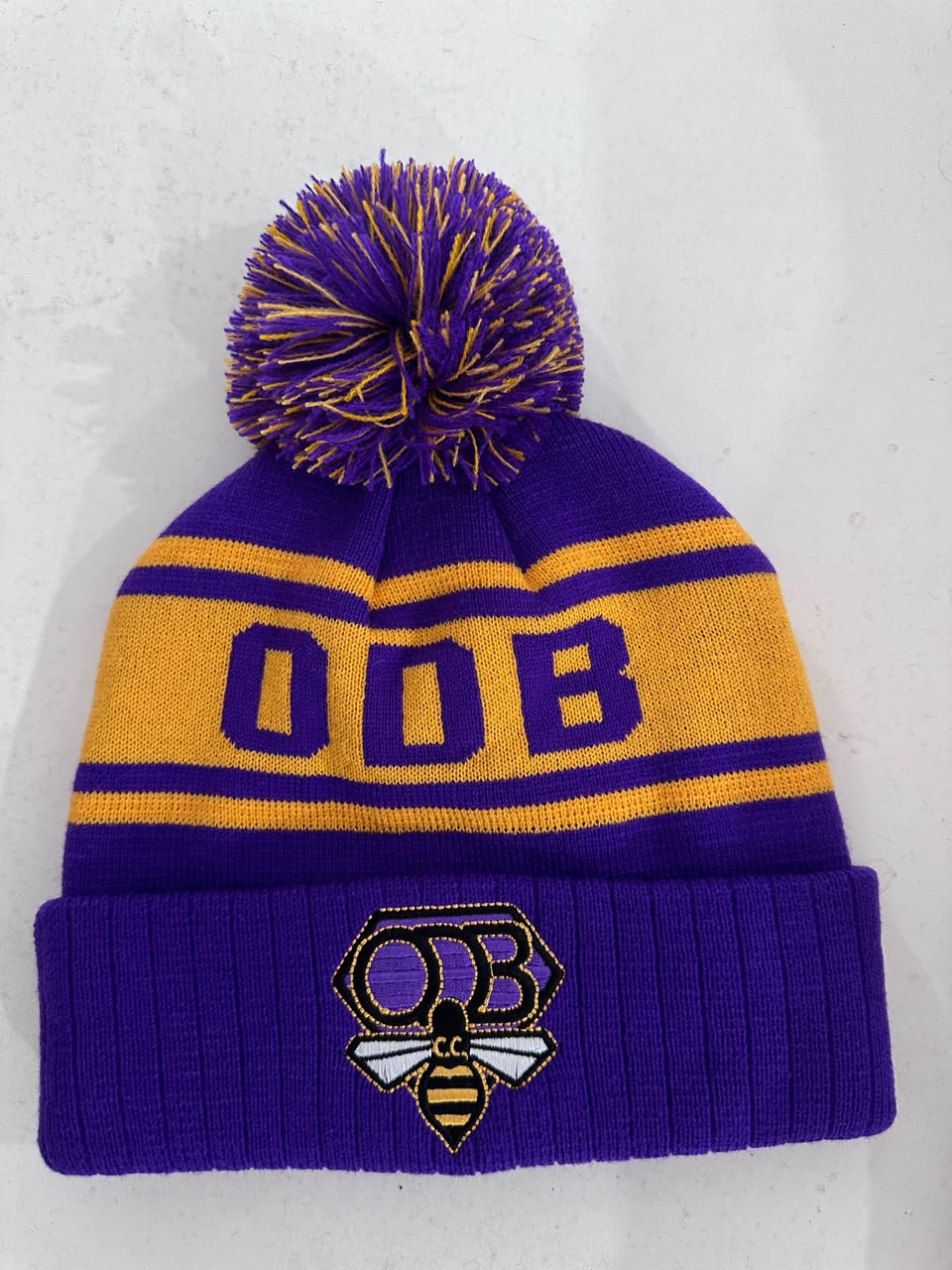 Custom purple and gold ODB CC bobble hat with embroidered bee crest