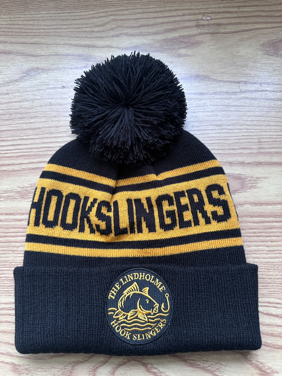 Custom black and gold Lindholme Hook Slingers bobble hat with circular embroidered patch
