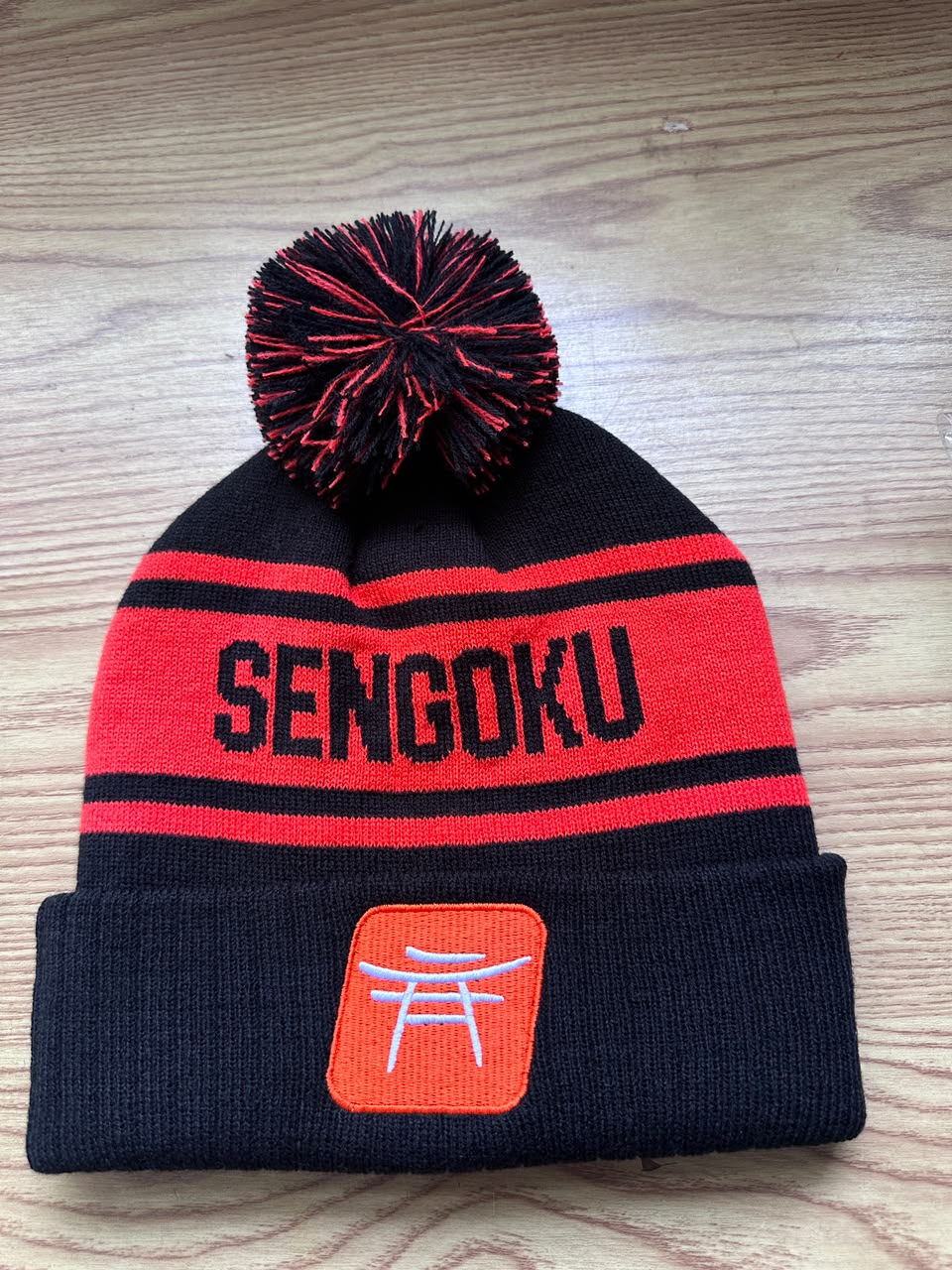 Custom black and red Sengoku bobble hat with orange torii gate embroidered patch