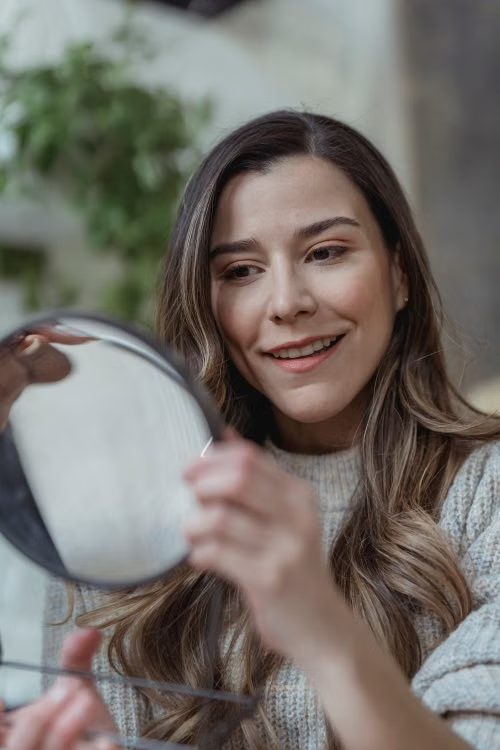 Donna che si osserva con uno specchio in un momento di introspezione e consapevolezza