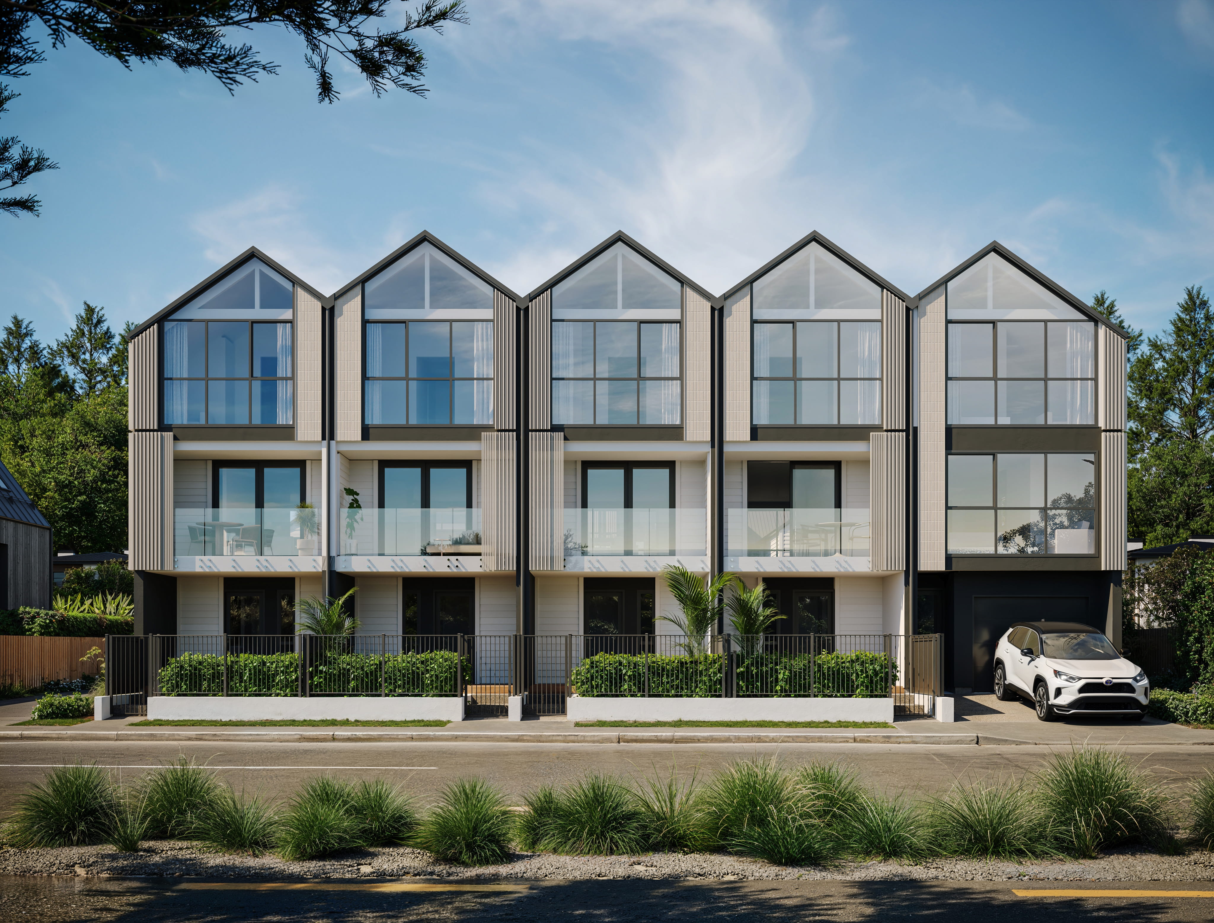 Artist's impression of the Seaside Place street elevation showing a row of contemporary gabled townhouses with light cladding, dark joinery, glass balconies and a carport, viewed from across Marine Parade under a bright New Brighton sky