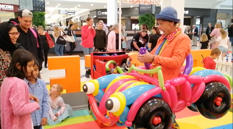 Silly Billy at a trade show with a balloon car