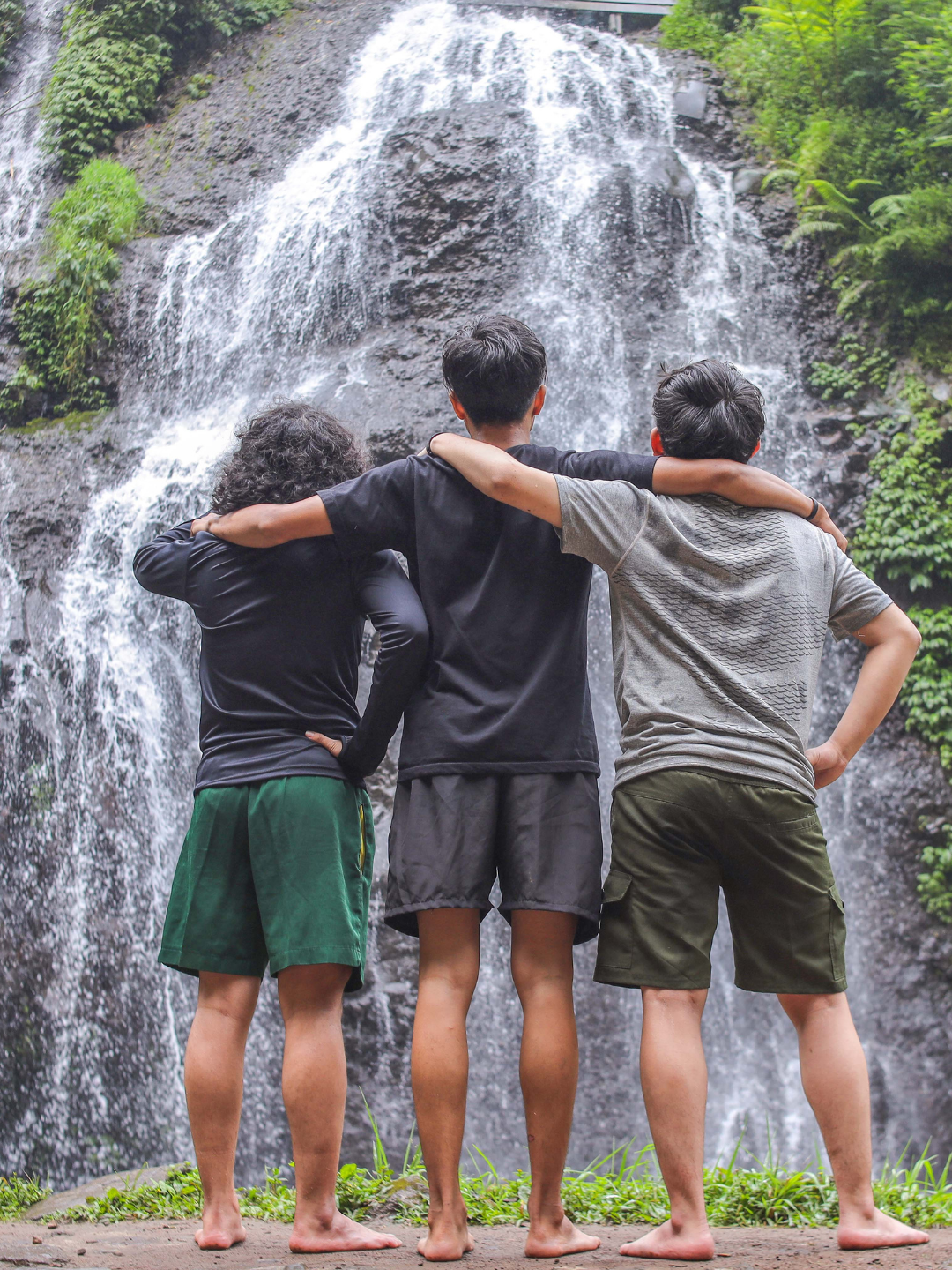Tre amici di spalle sotto una cascata
