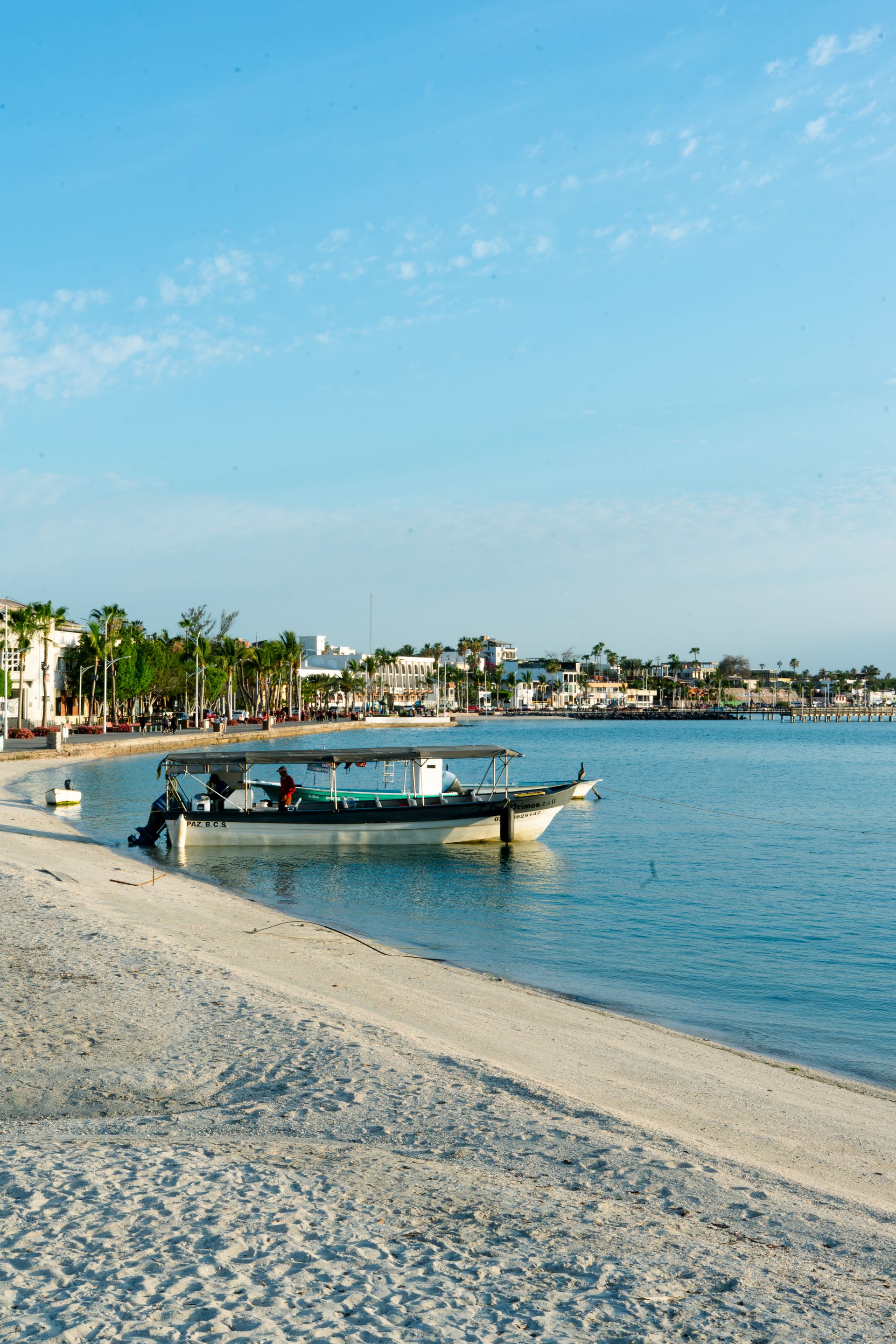 The malecón and beach of La Paz, looking over a boat anchored in the turquoise water