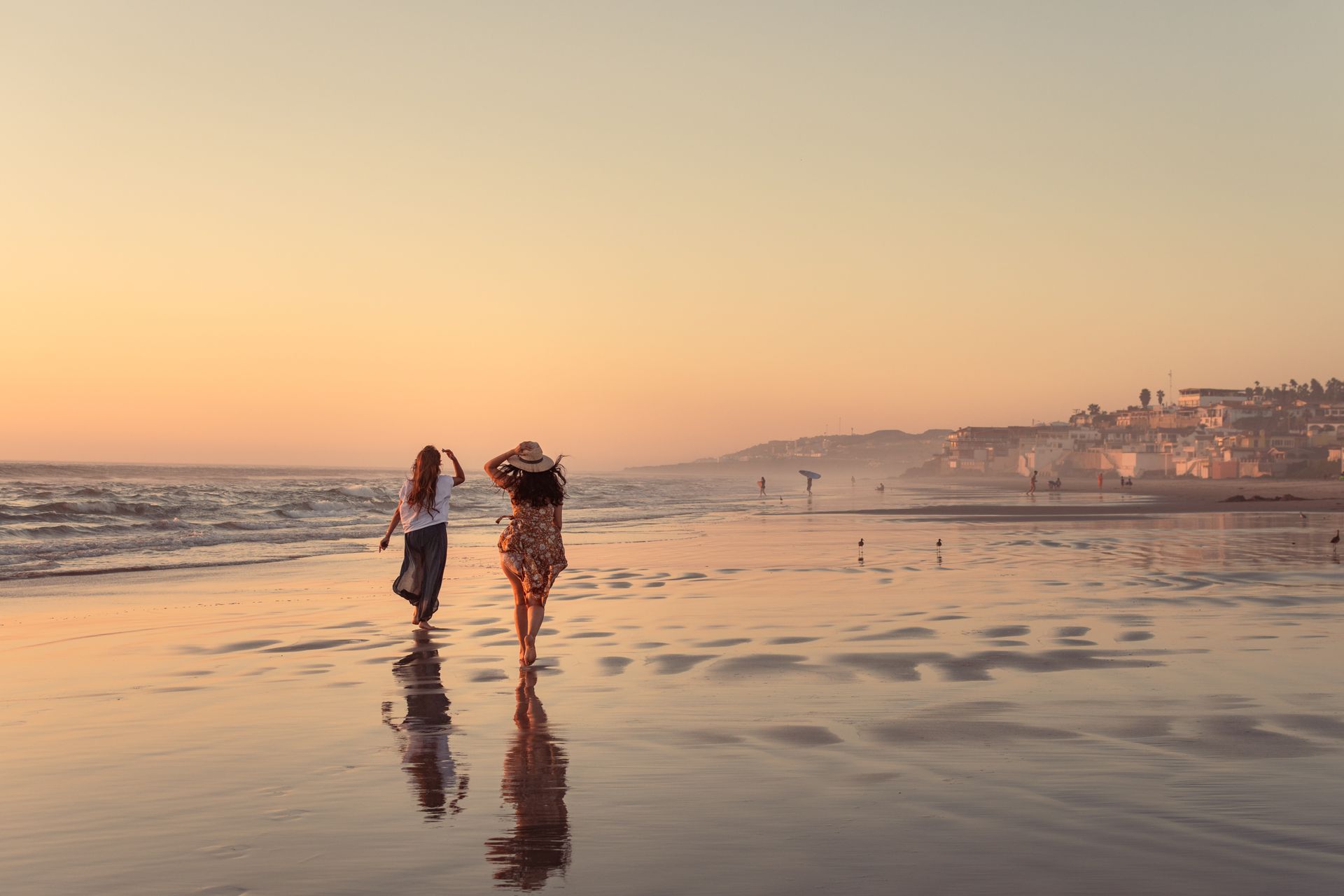 Golden hour on Rosarito beach with silhouettes of people walking along the shoreline reflections