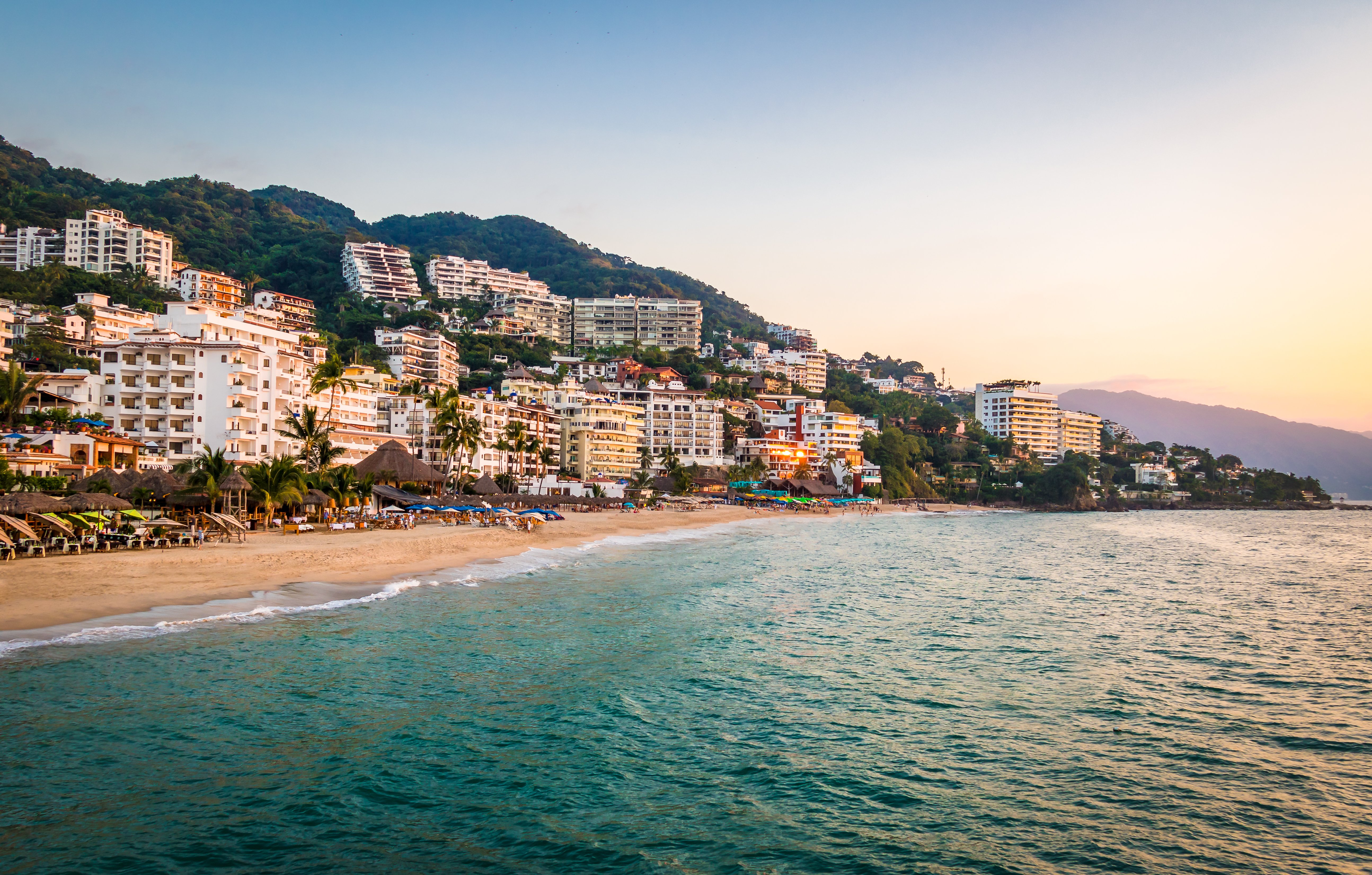 Panoramic dusk view of Puerto Vallarta coastline with luxury hillside buildings and the Pacific Ocean