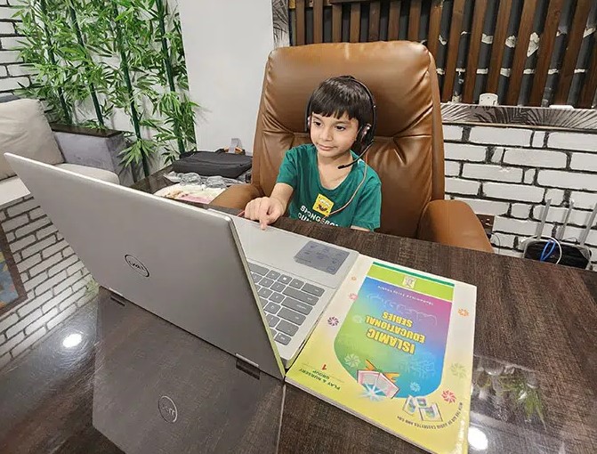 Young boy learning Quran online via laptop with TarteeleQuran teacher