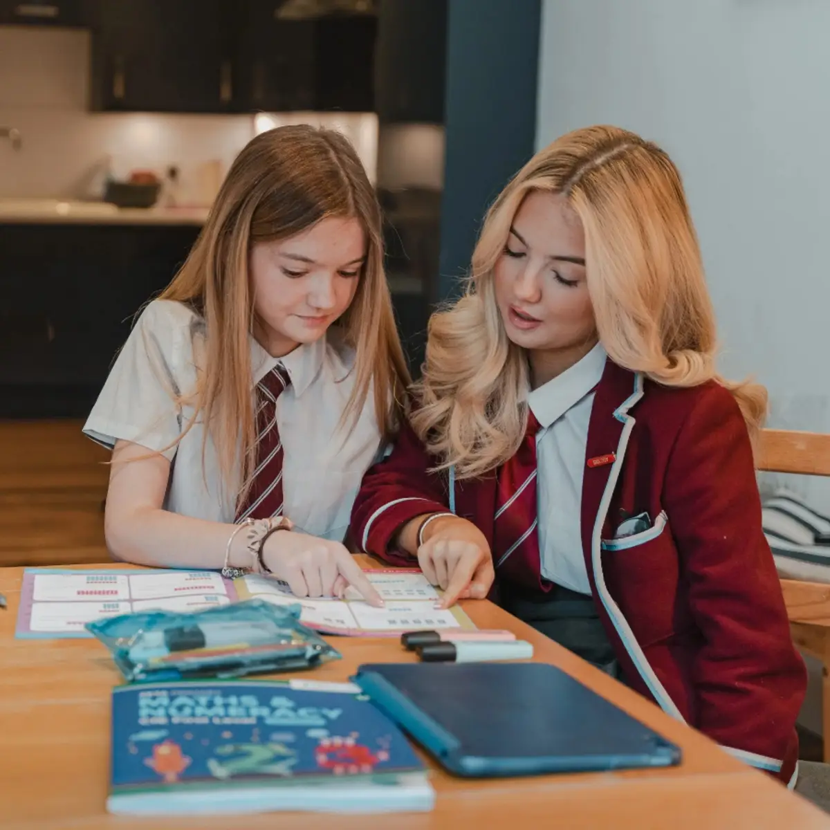 Two Scottish secondary school students in school uniform studying together with a ZETA Press maths textbook
