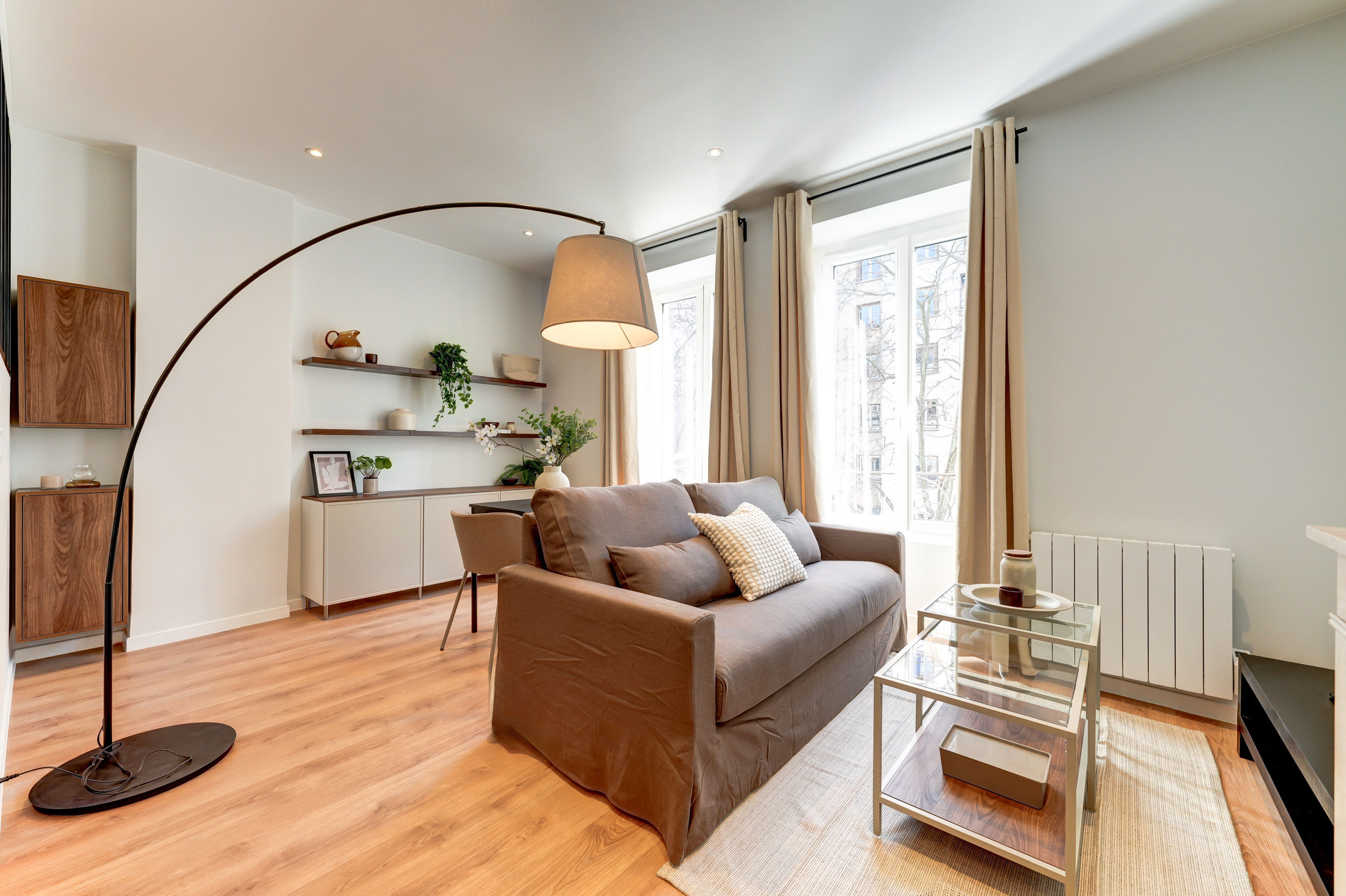 Salon lumineux avec lampadaire arche et canapé beige — pôle Gestion locative