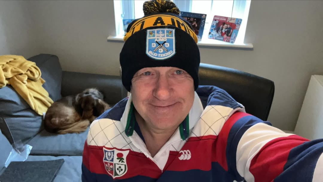Man in vintage British & Irish Lions rugby jersey wearing a navy and yellow ALTY AFC custom bobble hat, selfie at home with dog on sofa