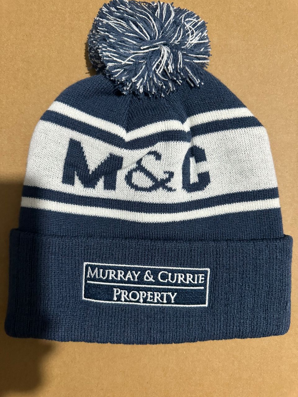 M&C custom navy and white chevron bobble hat with Murray & Currie Property sponsor patch