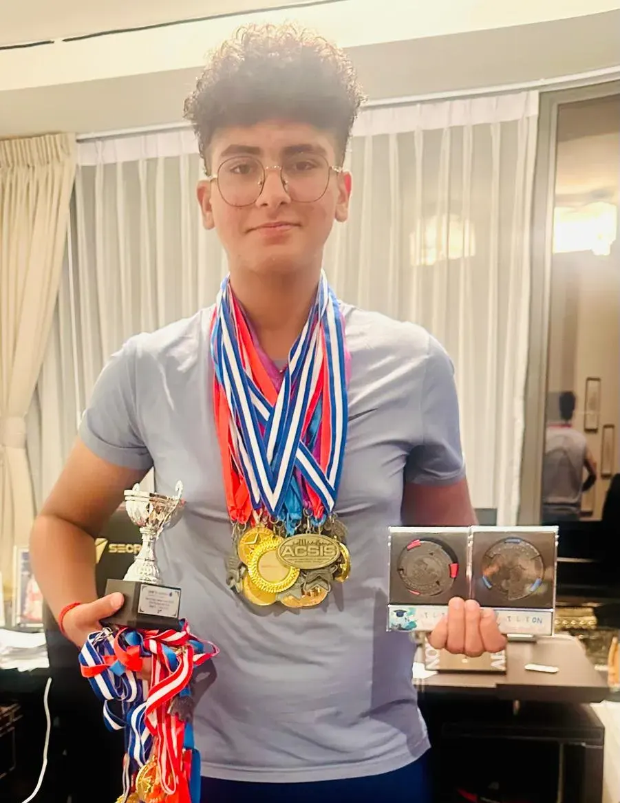 Aadi Sujan, Grade 7, holding trophies and medals from ACSIS and other national competitions