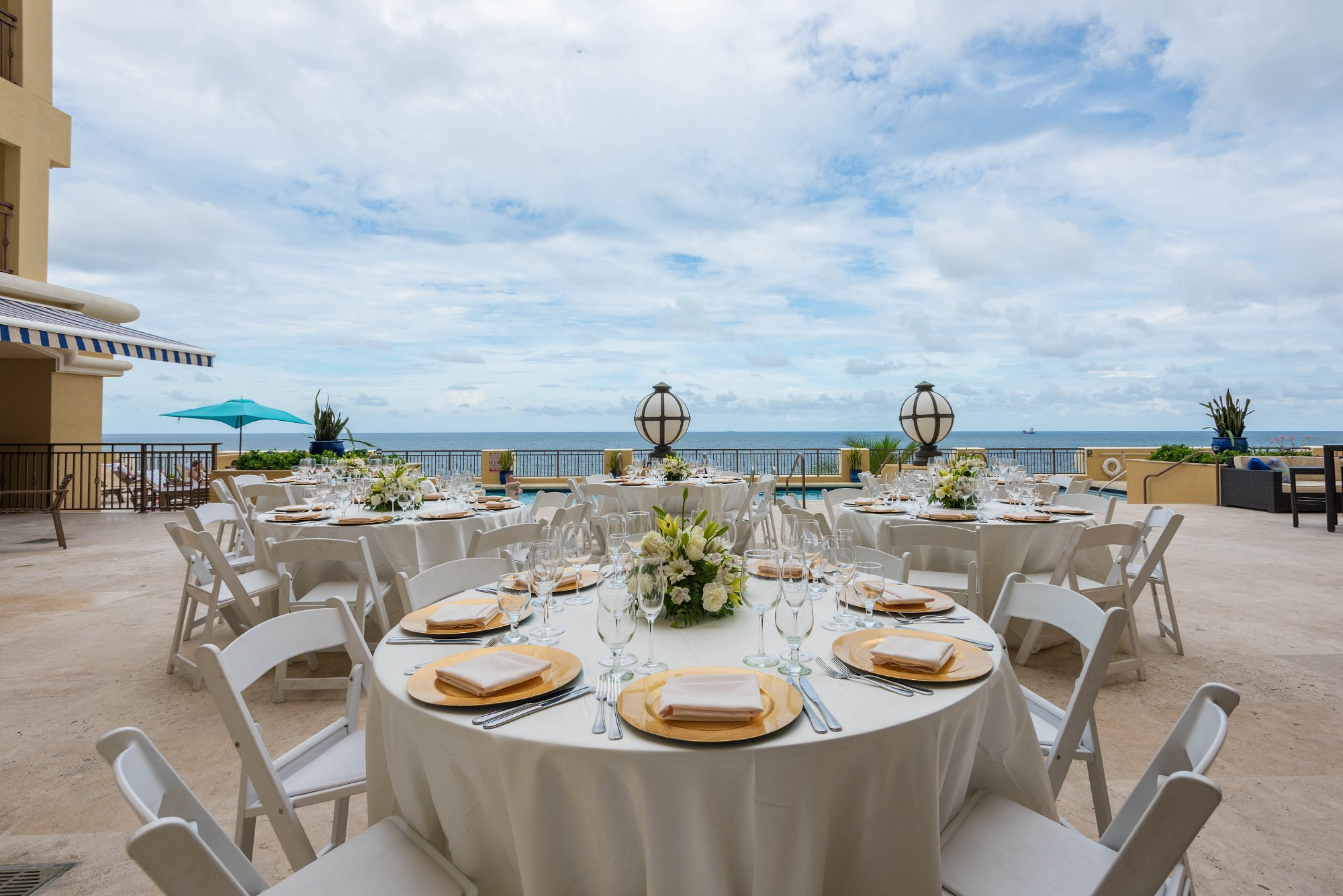 Pool deck set for group dinners and receptions with round tables and ocean view