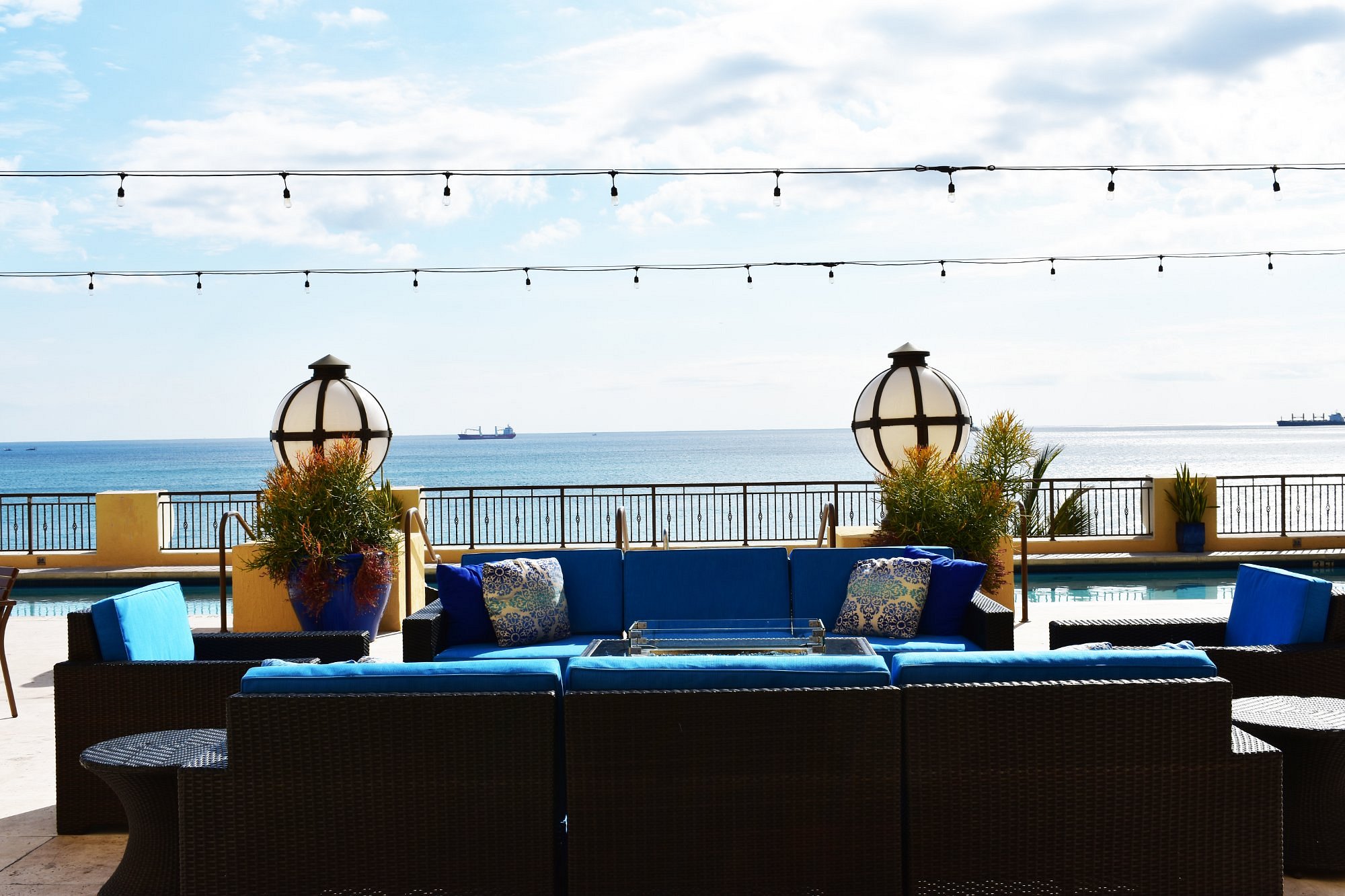 Pool deck with blue cushioned lounge seating overlooking the ocean