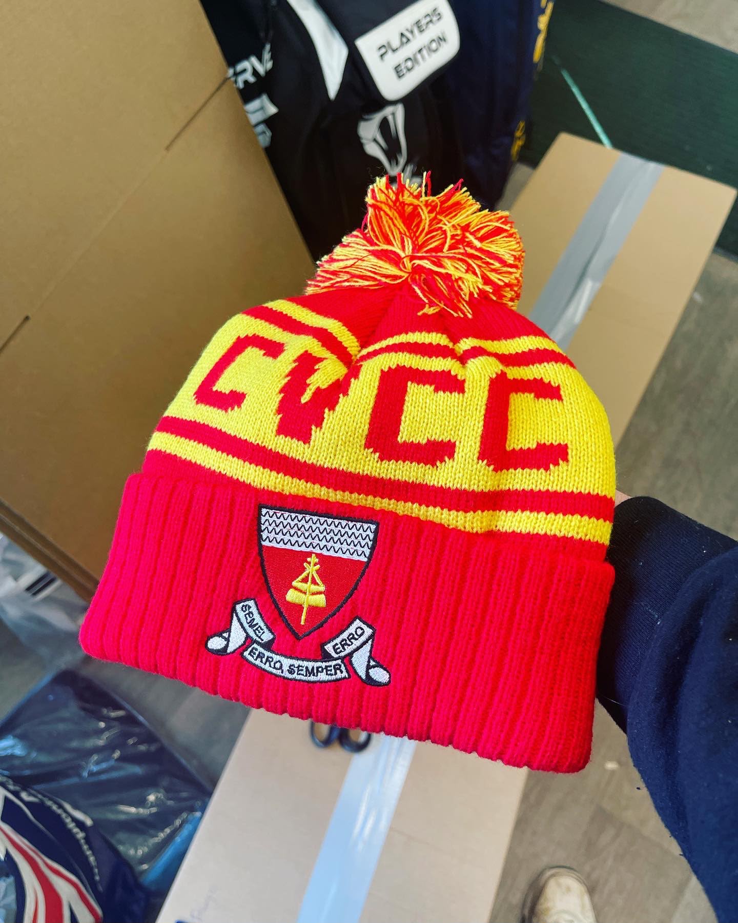 Clitne CC custom red and yellow bobble hat with yellow double-stripe band and embroidered shield crest with SEMEL ERRO SEMPER motto