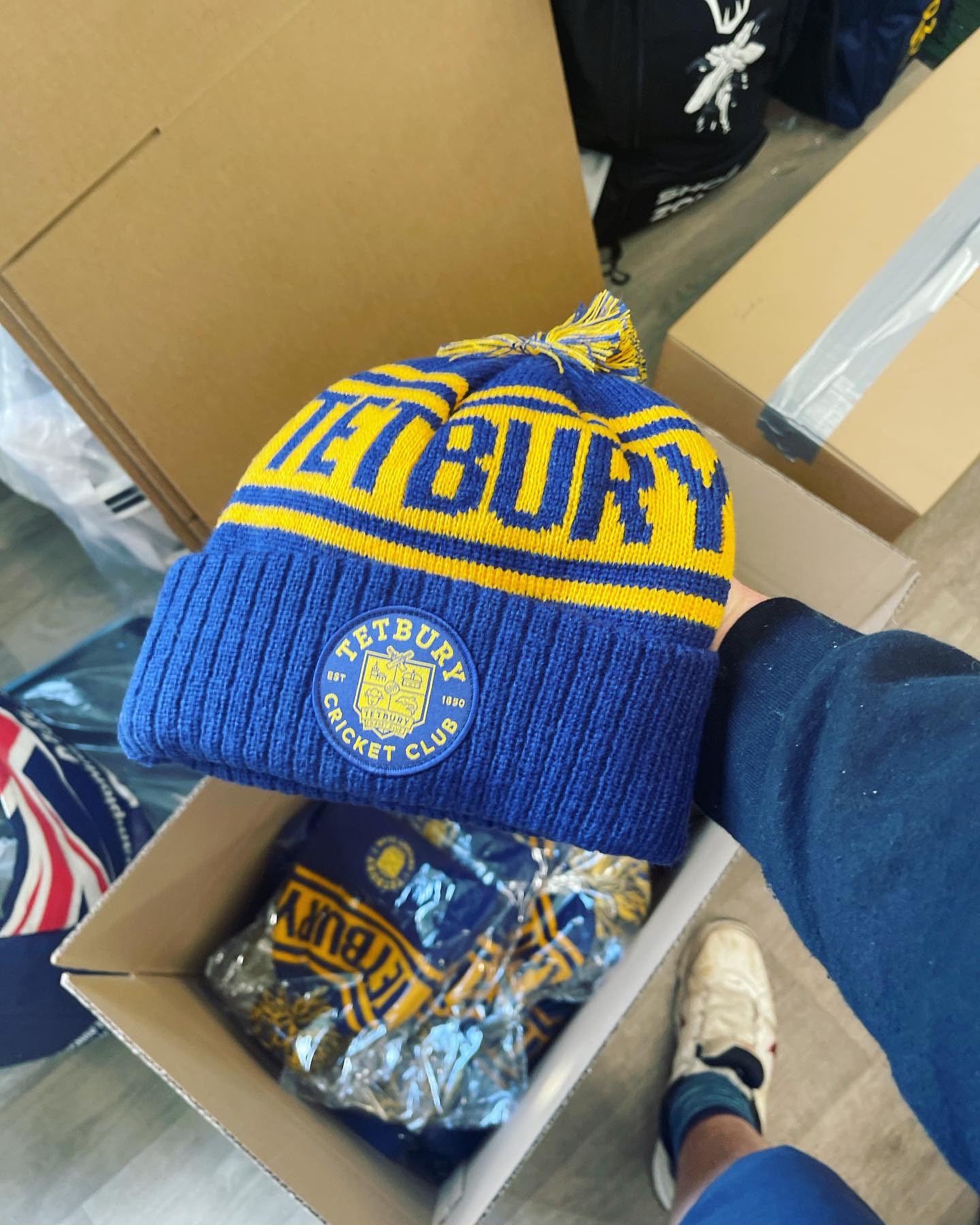 Tetbury Cricket Club custom royal blue and yellow bobble hat with TETBURY CRICKET CLUB round leather patch