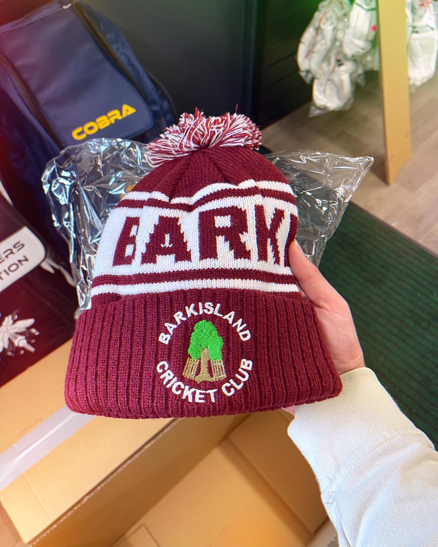 Barkisland Cricket Club custom maroon and white bobble hat with BARKISLAND CRICKET CLUB knitted band and embroidered green tree crest